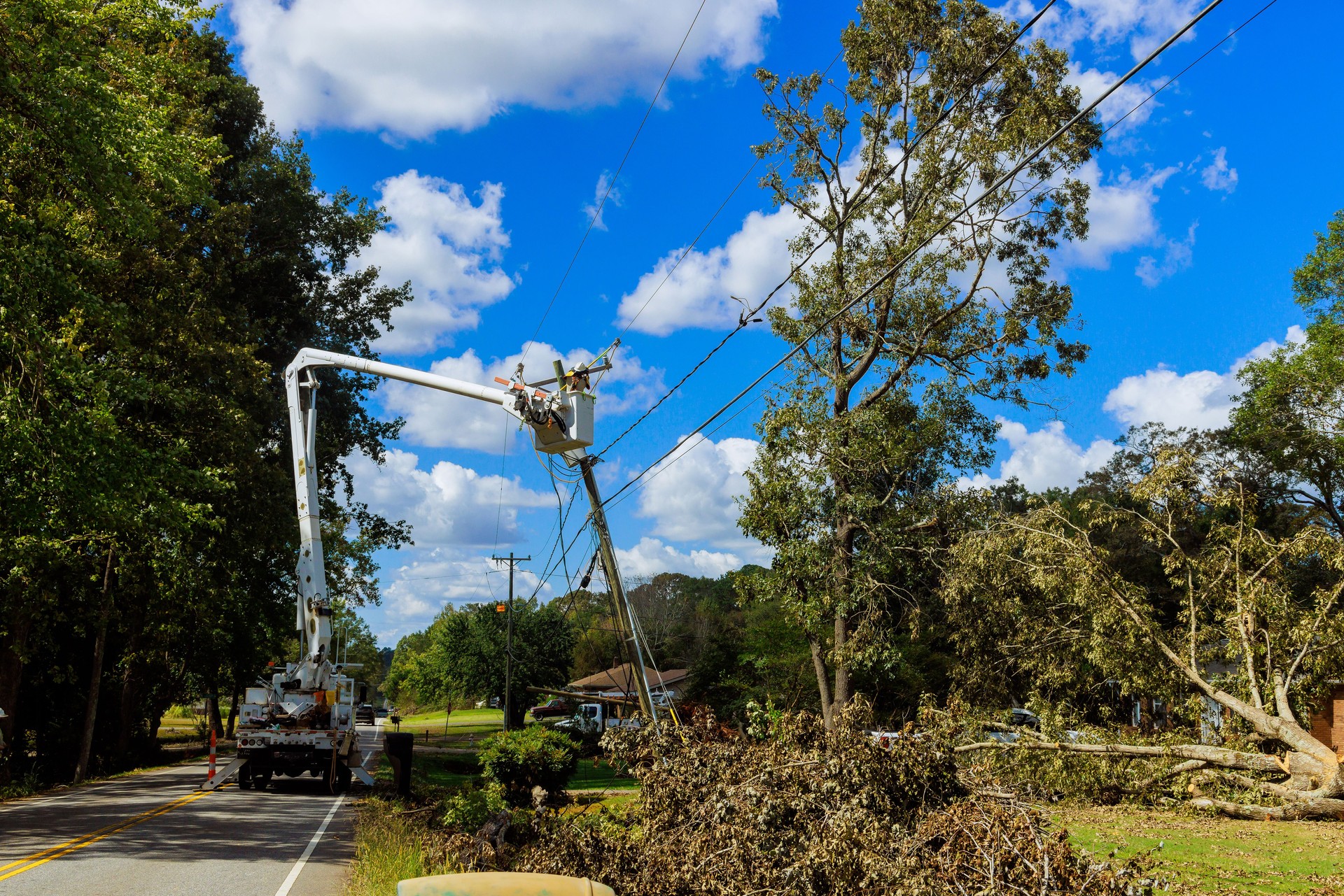 Emergency service linemen are diligently repairing power electrical lines damaged by a hurricane using utility tower trucks