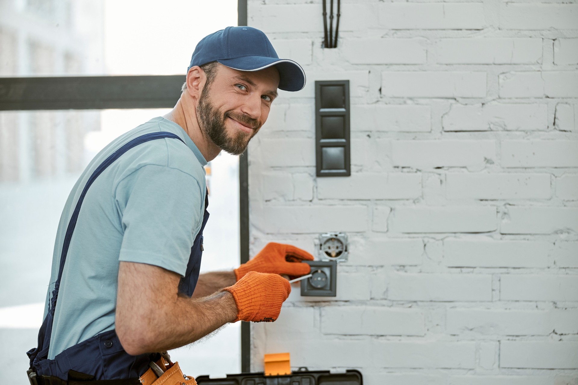 Cheerful young man fixing electrical wall socket